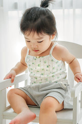 Toddler sitting in Avauma blue mint garden sleeveless top and gray shorts – comfy summer wear